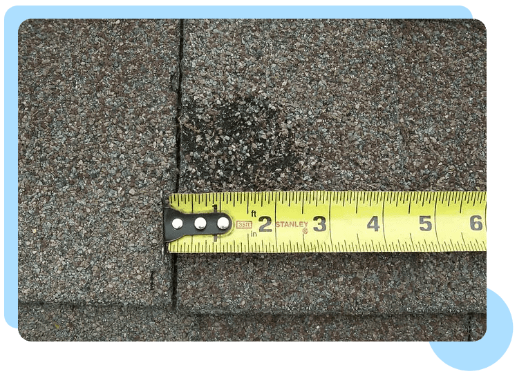 A yellow ruler is on the side of a roof.