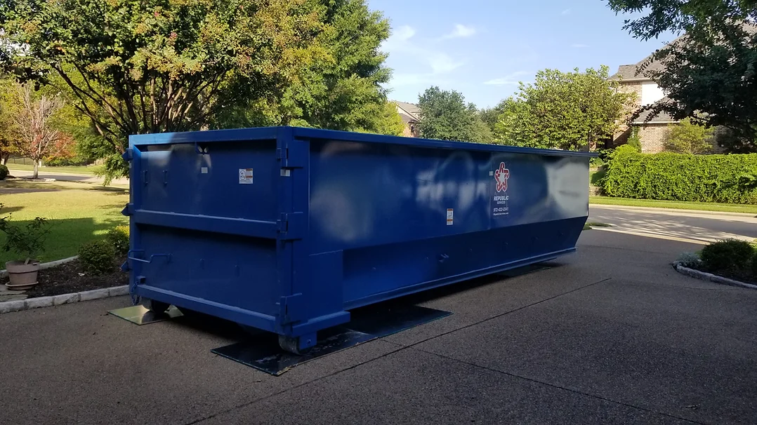 A blue dumpster sitting in the middle of a street.